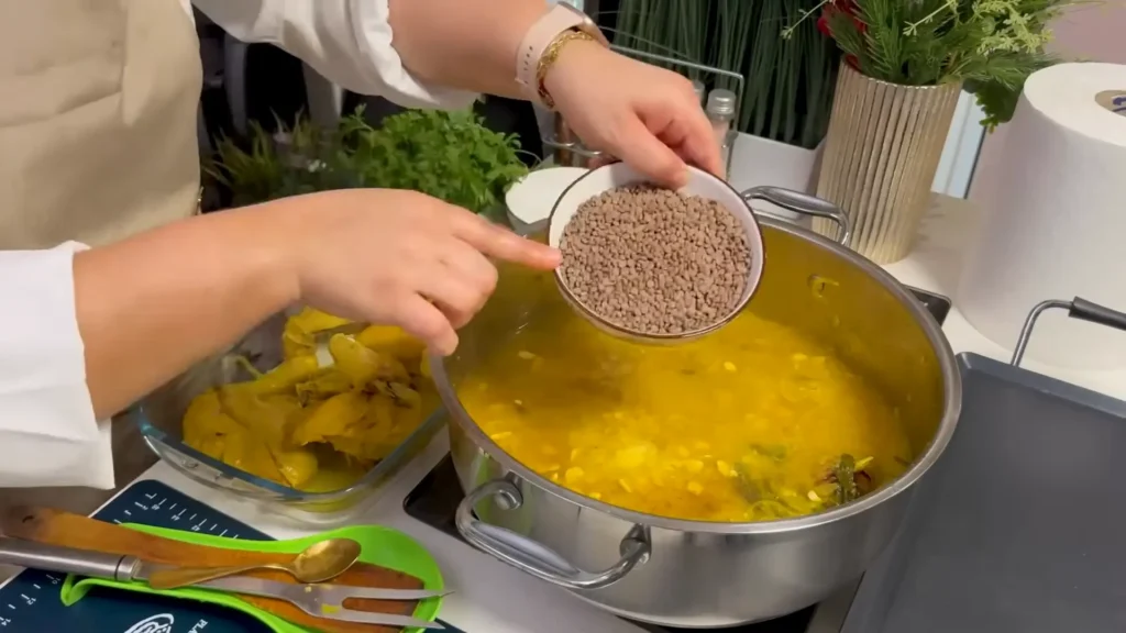 Lentils and fenugreek seeds being added to chicken and onions for Moroccan Rfissa