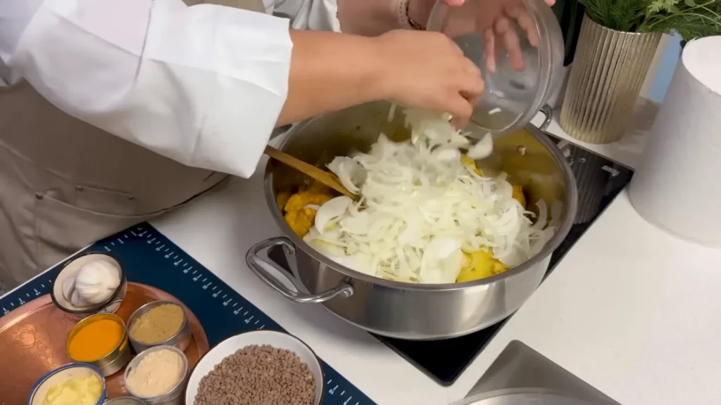 Onions, coriander, and parsley cooking with browned chicken for Moroccan Chicken Rfissa