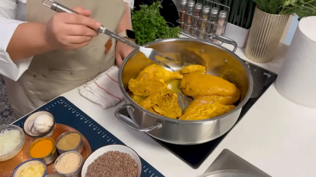 Chicken pieces browning in olive oil inside a pot for Moroccan Chicken Rfissa