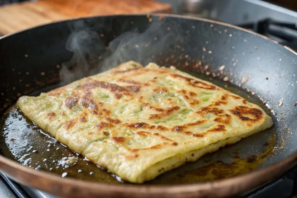 Msemen flatbread cooking in a pan with golden crisp edges